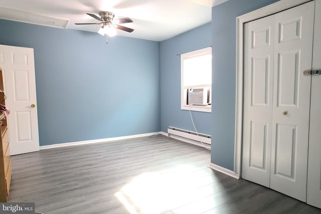 unfurnished bedroom with a baseboard heating unit, cooling unit, dark hardwood / wood-style floors, and ceiling fan