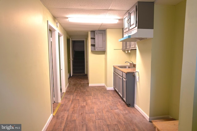 corridor featuring a paneled ceiling, sink, and dark hardwood / wood-style floors