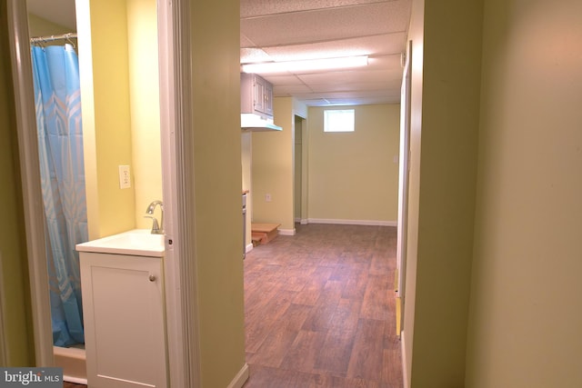 corridor with sink, dark hardwood / wood-style flooring, and a drop ceiling