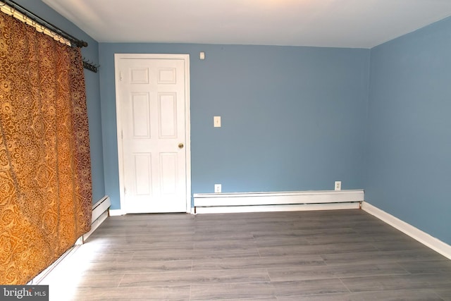 spare room featuring baseboard heating and wood-type flooring