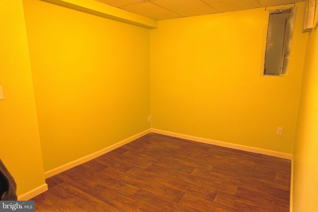 empty room featuring electric panel, a drop ceiling, and dark hardwood / wood-style floors