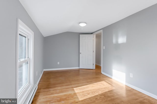 interior space featuring a baseboard radiator, light hardwood / wood-style floors, lofted ceiling, and plenty of natural light