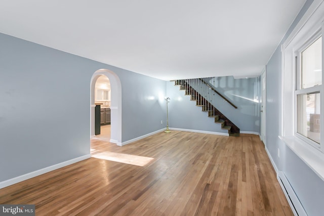 unfurnished room featuring baseboard heating and hardwood / wood-style flooring