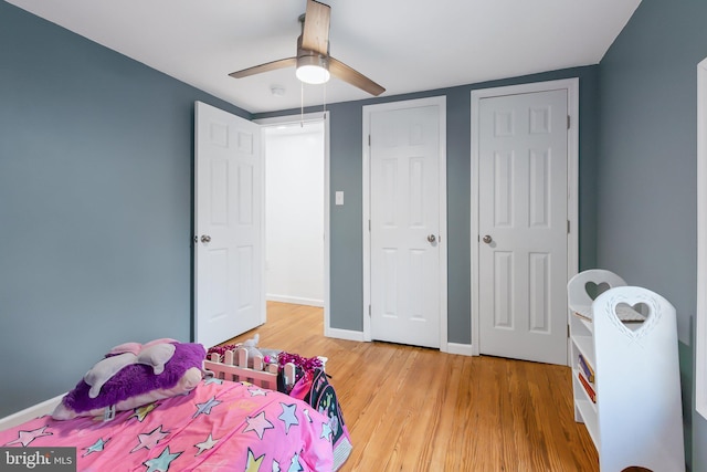 bedroom featuring multiple closets, hardwood / wood-style floors, and ceiling fan