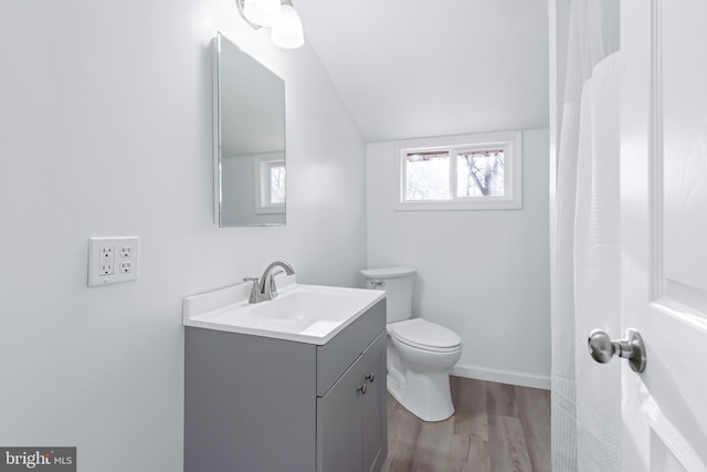 bathroom with toilet, hardwood / wood-style floors, vanity, and vaulted ceiling