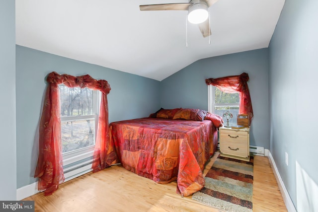 bedroom featuring lofted ceiling, a baseboard heating unit, light wood-type flooring, and ceiling fan