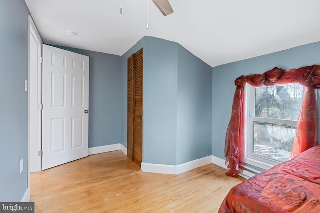 bedroom with a closet, vaulted ceiling, light hardwood / wood-style floors, and ceiling fan