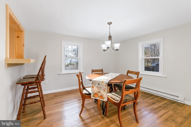 dining room featuring baseboard heating, an inviting chandelier, hardwood / wood-style flooring, and a healthy amount of sunlight