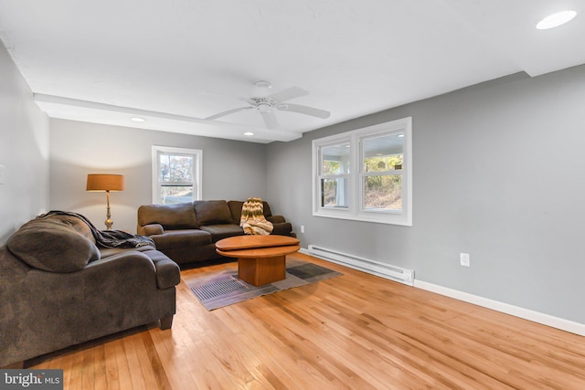 living room featuring light hardwood / wood-style floors, a baseboard heating unit, a healthy amount of sunlight, and ceiling fan