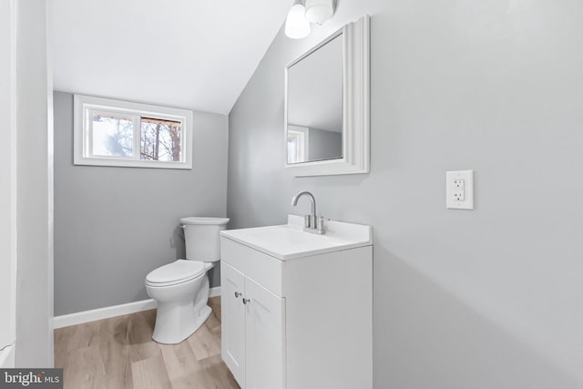 bathroom featuring toilet, lofted ceiling, hardwood / wood-style floors, and vanity