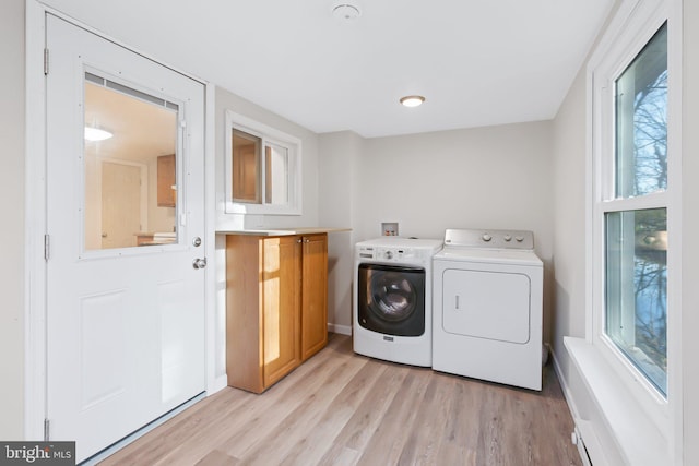 washroom with light hardwood / wood-style flooring, washing machine and dryer, and cabinets