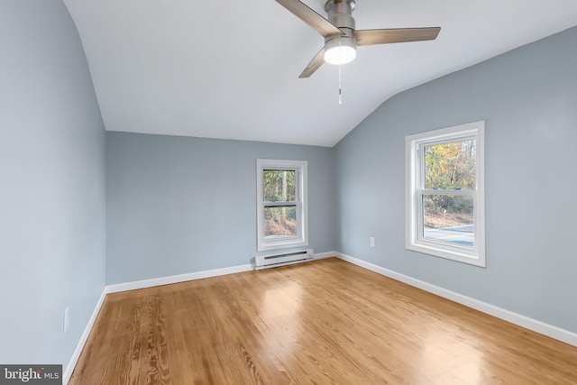 unfurnished room with light hardwood / wood-style floors, vaulted ceiling, a baseboard radiator, and ceiling fan