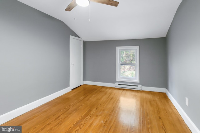 empty room with lofted ceiling, a baseboard heating unit, light wood-type flooring, and ceiling fan