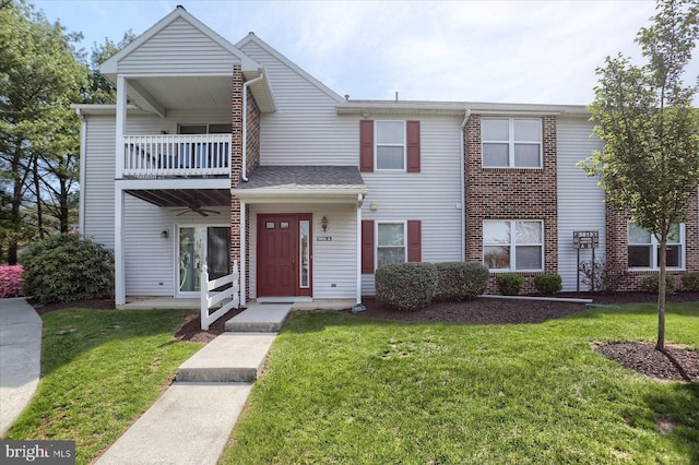 townhome / multi-family property with a ceiling fan, a front lawn, and a balcony