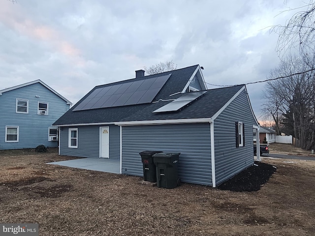 back of property with a patio area and solar panels