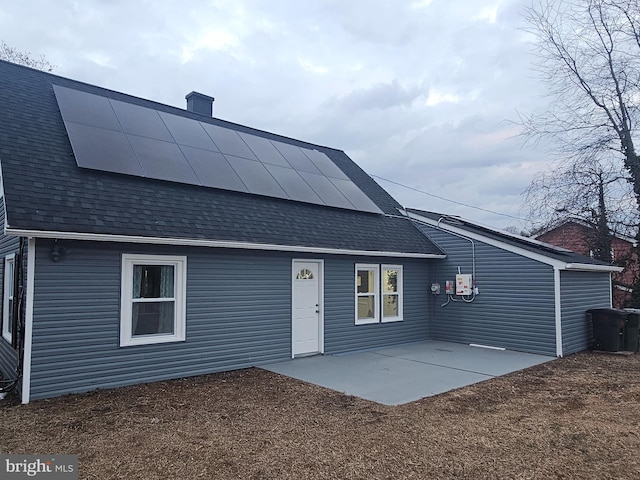 back of house with a patio area and solar panels