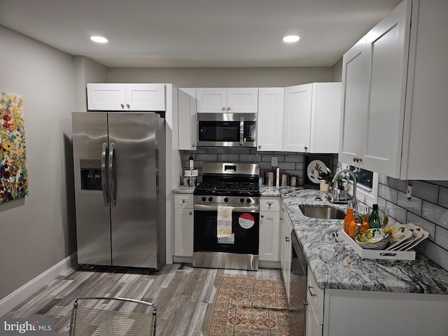 kitchen with light stone countertops, white cabinets, appliances with stainless steel finishes, and tasteful backsplash