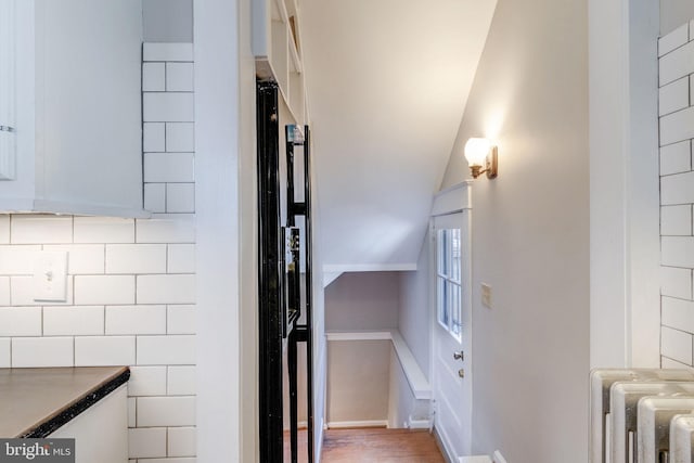 stairway featuring radiator heating unit, lofted ceiling, and wood-type flooring