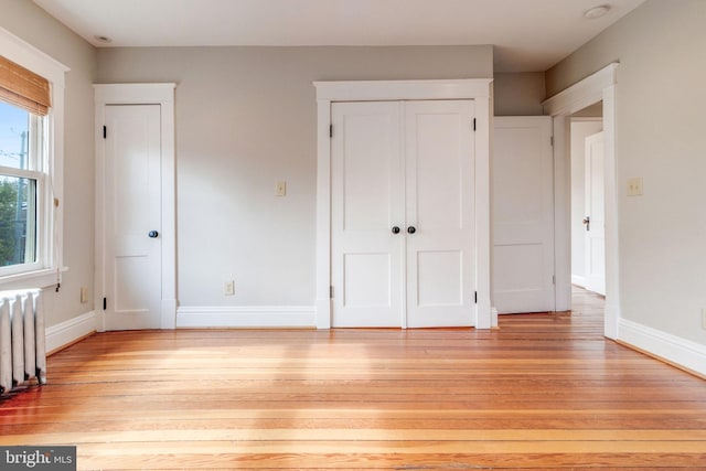 unfurnished bedroom featuring radiator heating unit and light wood-type flooring