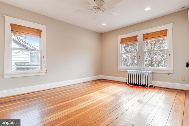 spare room with light hardwood / wood-style flooring, ceiling fan, and radiator