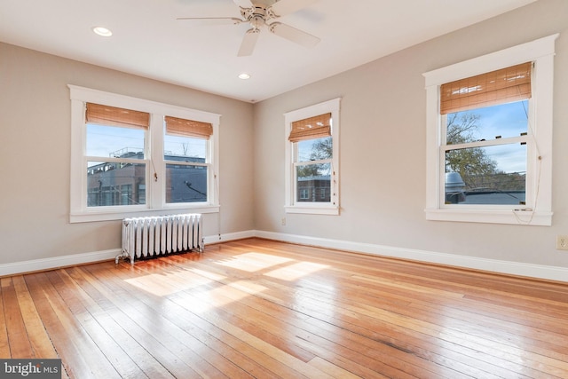 spare room with radiator heating unit, ceiling fan, and light hardwood / wood-style flooring