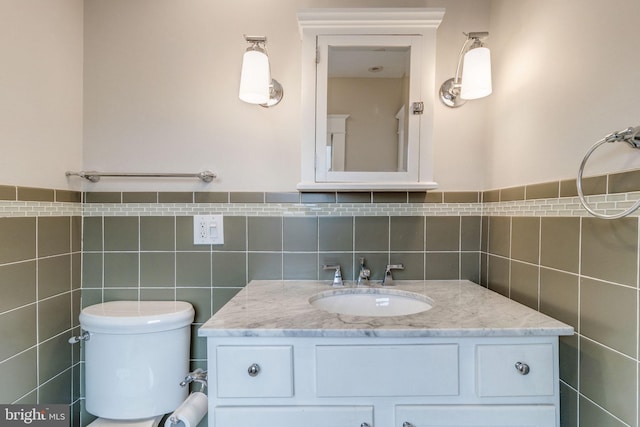 bathroom with tile walls, vanity, and toilet