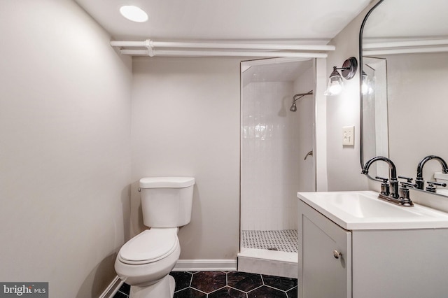 bathroom with toilet, tiled shower, tile patterned floors, and vanity