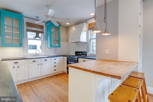 kitchen with pendant lighting, a wealth of natural light, premium range hood, and black gas range