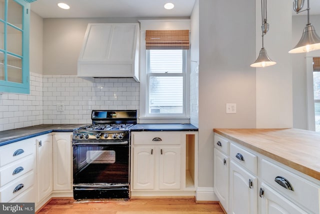 kitchen with black range with gas stovetop, custom exhaust hood, white cabinetry, light hardwood / wood-style flooring, and decorative light fixtures