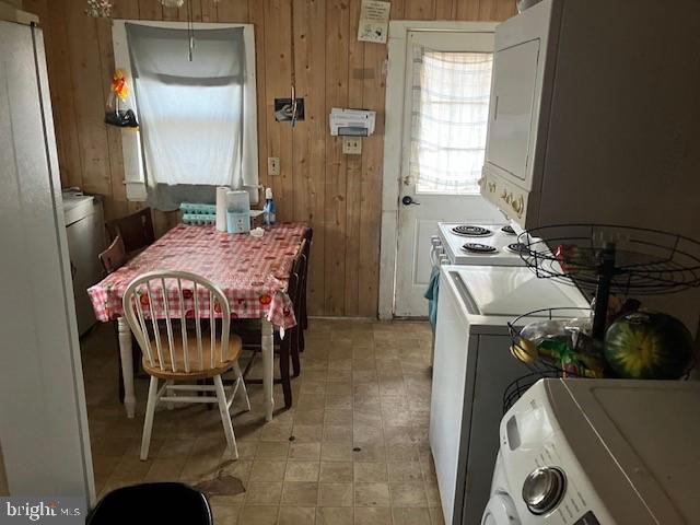 kitchen with white cabinets, stacked washing maching and dryer, and wooden walls