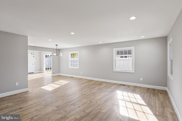 spare room featuring an inviting chandelier and light hardwood / wood-style flooring