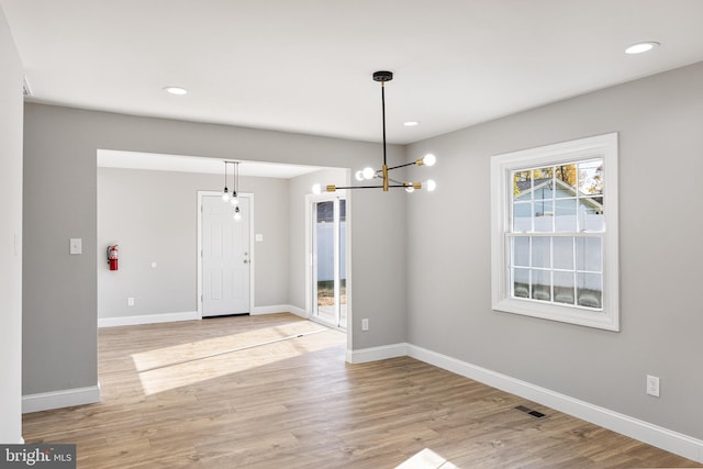 unfurnished dining area featuring light hardwood / wood-style flooring and an inviting chandelier