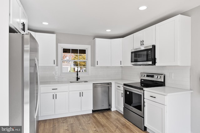 kitchen featuring white cabinetry, sink, decorative backsplash, appliances with stainless steel finishes, and light wood-type flooring