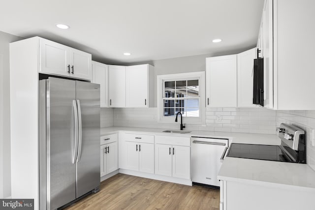 kitchen featuring appliances with stainless steel finishes, light hardwood / wood-style flooring, white cabinetry, and sink