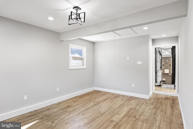 spare room with light hardwood / wood-style floors and an inviting chandelier