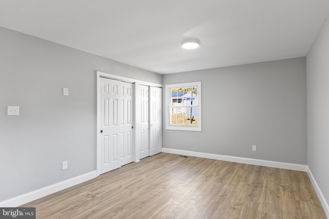 unfurnished bedroom featuring light hardwood / wood-style floors and two closets