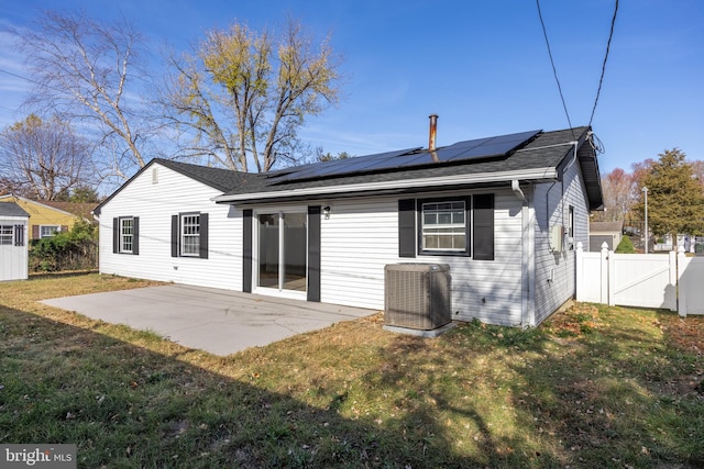 rear view of property with a lawn, central air condition unit, a patio, and solar panels