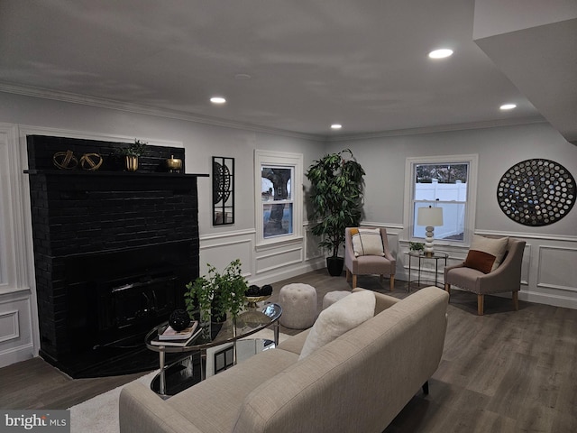 living room with hardwood / wood-style flooring, crown molding, and a brick fireplace