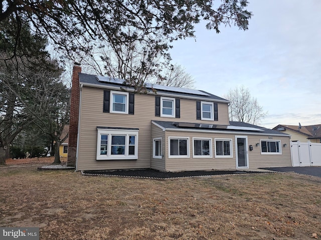 view of property with solar panels and a front lawn