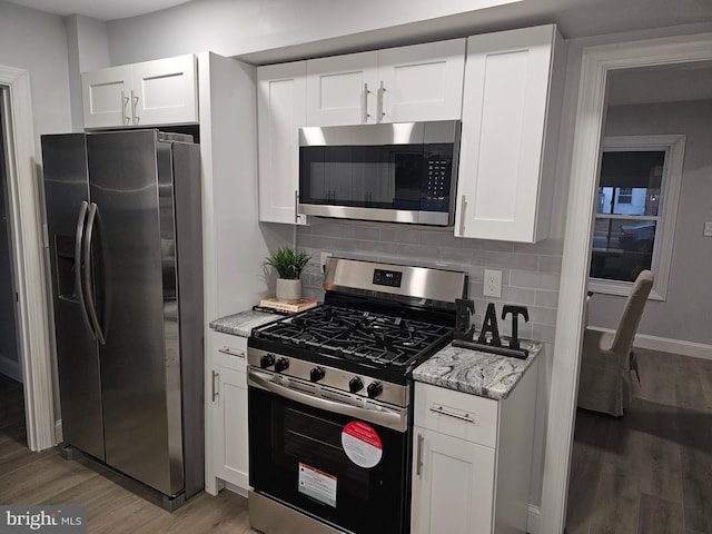 kitchen with appliances with stainless steel finishes, hardwood / wood-style flooring, and white cabinetry