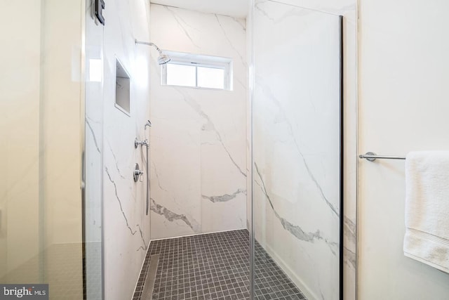 bathroom with a tile shower and tile patterned flooring