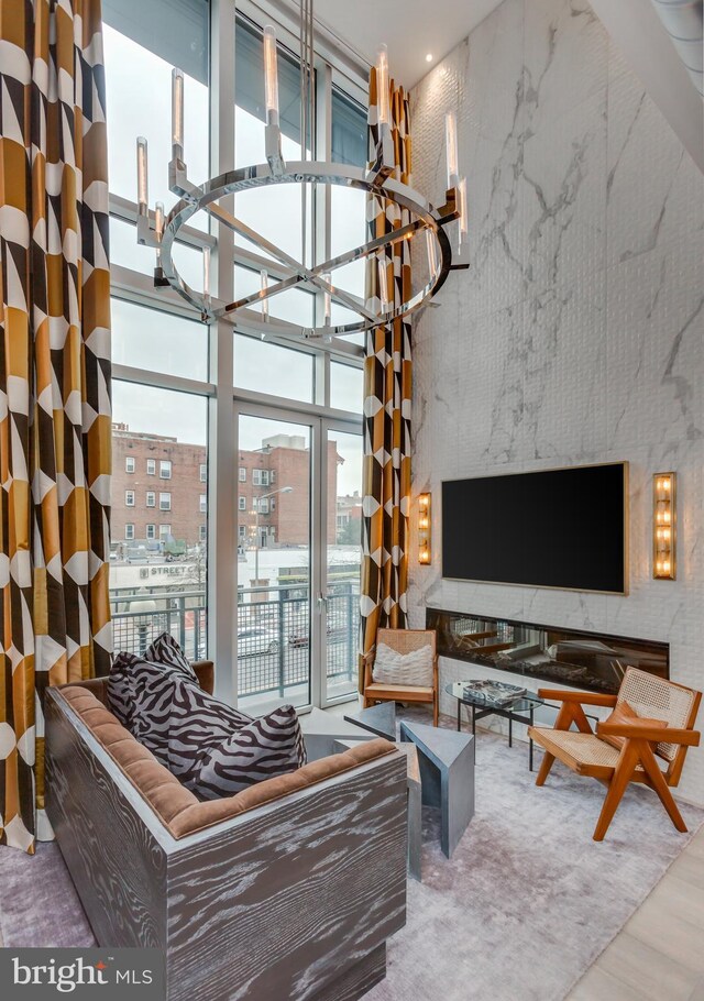 living room featuring a notable chandelier, hardwood / wood-style flooring, a towering ceiling, and expansive windows