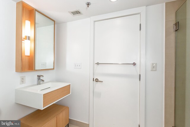 bathroom featuring sink and a shower with shower door