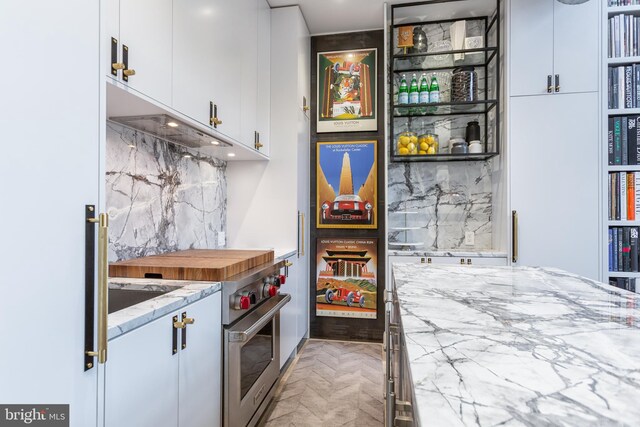 bar with white cabinetry, light stone counters, stainless steel stove, and backsplash