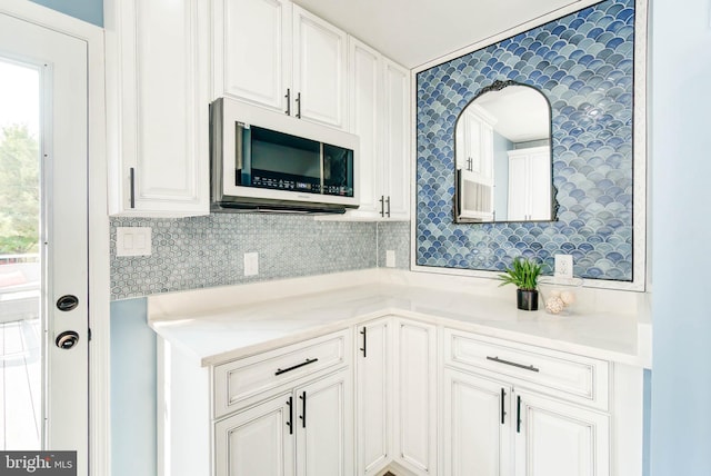 kitchen with white cabinets, backsplash, a healthy amount of sunlight, and light countertops