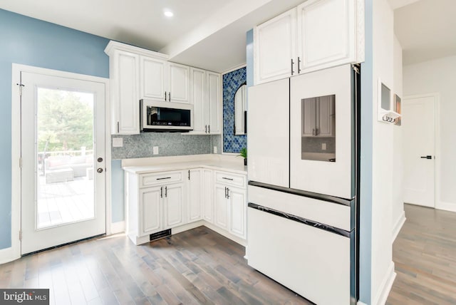 kitchen with dark wood-style floors, decorative backsplash, white cabinetry, light countertops, and freestanding refrigerator