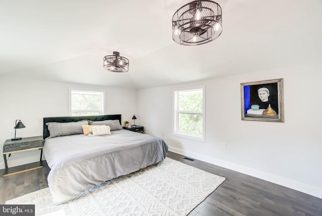 bedroom featuring baseboards, visible vents, wood finished floors, and vaulted ceiling