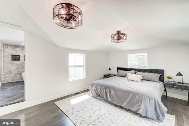 bedroom with an inviting chandelier, lofted ceiling, visible vents, baseboards, and wood finished floors