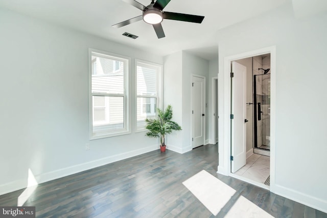 unfurnished bedroom featuring visible vents, ceiling fan, baseboards, wood finished floors, and ensuite bath