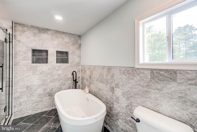 bathroom with toilet, tile walls, tile patterned flooring, and plus walk in shower